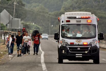 Una ambulancia pasa junto a migrantes que caminan por la carretera hacia Ciudad de México.