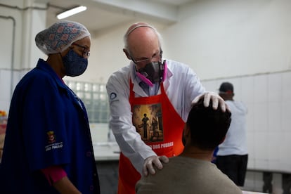 Padre Júlio Lancellotti acolhe um morador de rua de São Paulo junto com uma agente social da Prefeitura.