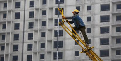 Un obrero trabaja sobre un andamio para encofrado en las obras de construcción de un edificio