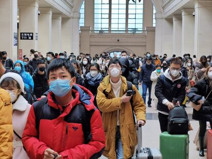 Viajeros, todos con mascarilla (cuyo uso es obligatorio en espacios públicos), en la estación ferroviaria de Hankou, en Wuhan, este miércoles, donde las autoridades han colocado una reja en los todos los accesos menos en uno. Ante el anuncio del cierre de la ciudad, muchos pusieron rumbo al aeropuerto y las estaciones de tren antes de que este entrase en vigor.