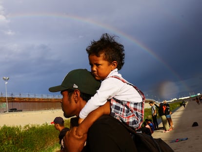 Un hombre carga a su hijo mientras busca asilo en Estados Unidos, a orillas del río Bravo, el 12 de septiembre de 2023.