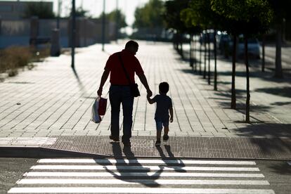 Un niño junto a su padre camina hacia el colegio en el primer día del curso escolar.