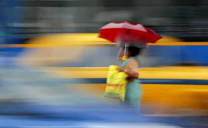 Una mujer trata de cruzar una calle de Calcuta (India) en un día de lluvia.