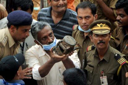 Un miembro de la Dirección General de la Aviación Civil india muestra un objeto hallado durante la búsqueda de la <i>caja negra</i> del avión estrellado el sábado en Mangalore.
