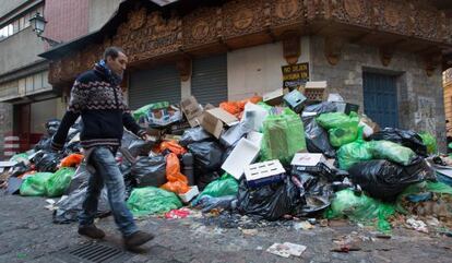 Un hombre pasa junto a la basura acumulada en una calle del centro de Granada.