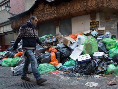 Un hombre pasa junto a la basura acumulada en una calle del centro de Granada.