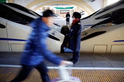 Un pasajero pasa deprisa por delante de un trabajador de la estación central de trenes de Pekín.