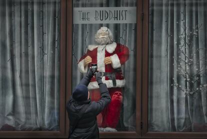Un hombre toma imágenes de un gran maniquí de Papá Noel, decorando un escaparate en Bucarest, Rumania.
