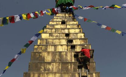 Un trabajador nepalés desciende de la estupa Dhando Chaitya después de colgar la bandera de oración en Katmandú, Nepal.