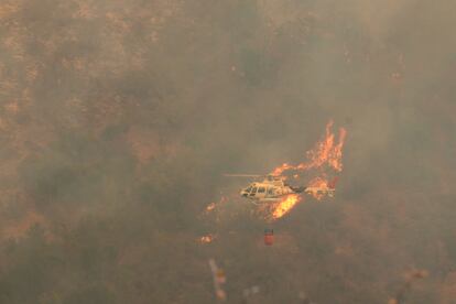 Un helicóptero sobrevuela un incendio forestal que se ha extendido en la región de Valparaíso. 