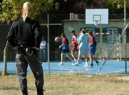 Una vigilante de seguridad observa cómo juegan al baloncesto las menores del centro El Madroño.