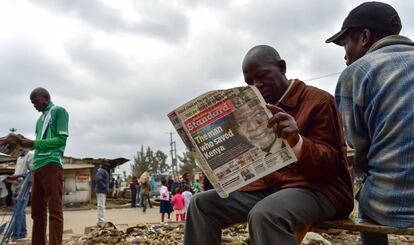 Dos hombres leyendo un periódico local con la portada dedicada a Koffi Annan.