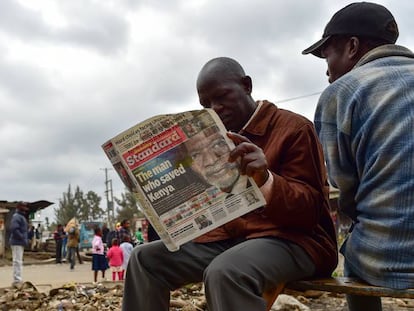 Dos hombres leyendo un periódico local con la portada dedicada a Koffi Annan.