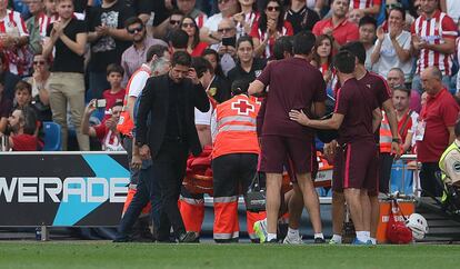 El entrenador del Atlético de Madrid, Diego Pablo Simeone, asiente mientras es atendido su jugador José María Giménez.