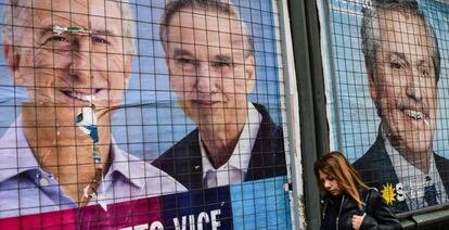 Una mujer pasea junto a carteles electorales de Mauricio Macri y Alberto Fernández, candidatos a presidir Argentina.