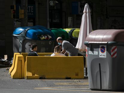 La terraza de un bar en pleno chaflán de la calle Aragón, entre contenedores de basura y reciclaje.