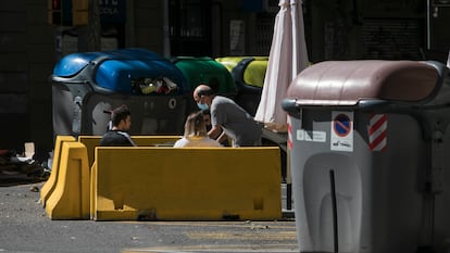 La terraza de un bar en pleno chaflán de la calle Aragón, entre contenedores de basura y reciclaje.