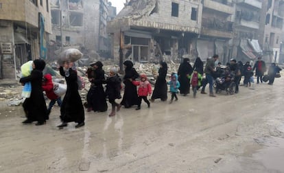 Civis e crianças sírias abandonam um bairro de Aleppo de Bustan Al-Qasr em direção ao de Fardos, em 13 de dezembro