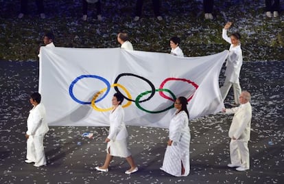 Silva saluda mientras porta la bandera olímpica junto a otras personalidades.