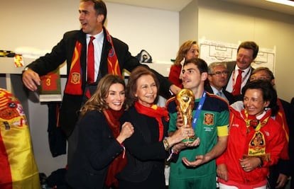 Don Felipe, con do&ntilde;a Letizia y do&ntilde;a Sof&iacute;a, detr&aacute;s de Casillas, capit&aacute;n de la selecci&oacute;n nacional de f&uacute;tbol en el vestuario tras la victoria de Espa&ntilde;a en Sud&aacute;frica en 2010.