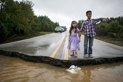 Miranda Chio, 4 and her brother Alex Chio, 10, look at York Creek where the road has washed away in Driftwood, Hays County, Texas October 30, 2015. High winds and heavy rains pelted central Texas on Friday, flooding highways, causing evacuations after rivers overflowed their banks and creating tornadoes that ripped through buildings outside San Antonio. More than 200 low-water crossings were closed due to the storm, which hit in the same area where flooding in late May caused more than 20 deaths. REUTERS/Ilana Panich-Linsman EDITORIAL USE ONLY. NO RESALES. NO ARCHIVE