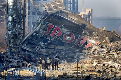 Un grupo de personas examinan los daños causados tras el bombardeo de un centro comercial, en Kiev. Los ciudadanos ucranianos, en su mayoría mujeres, niños y personas mayores, que han dejado su país a consecuencia de la invasión rusa se elevan a 3,48 millones, según las cifras que muestra hoy la Agencia de la ONU para los Refugiados (ACNUR).