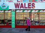 (FILES) In this file photo taken on September 27, 2020 a woman wearing a protective face visor walks past a souvenir shop selling Welsh-themed items, in Cardiff, south Wales. - Wales will impose a full "firebreak" lockdown for two weeks from October 23, to try to reduce a soaring number of new coronavirus cases, First Minister Mark Drakeford said on October 19, 2020. Under the new rules, everyone will be required to stay at home with only critical workers expected to go to their workplaces. (Photo by Geoff Caddick / AFP)