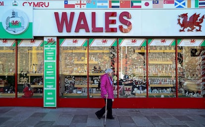 Una mujer con pantalla facial protectora camina por el centro de Cardiff, en Gales.