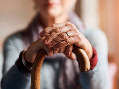 Una anciana se apoya sobre su bastón.