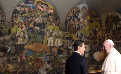 El papa Francisco (d) conversa con el presidente de México Enrique Peña Nieto, con el mural de Diego Rivera que representa la historia de México en el Palacio Nacional en la Ciudad de México.