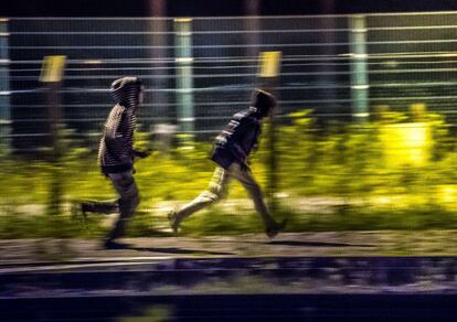 Unos inmigrantes otro lugar de acceso a la terminal del Eurotunel cerca de Calais, después de traspasar la primera valla.