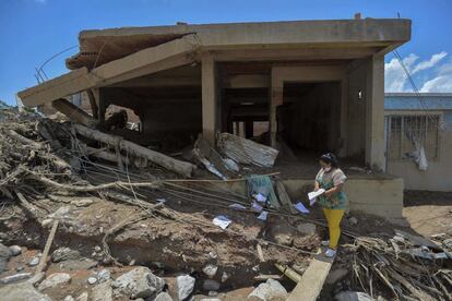 Una mujer mira el cuaderno de su hijo en mitad de los escombros de su casa, ahora en ruinas por las inundaciones del 1 de abril.
