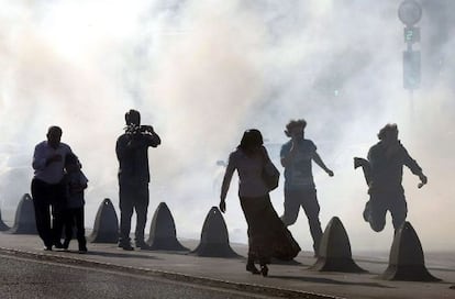 Personas intentan escapar de las balas de gas lacrim&oacute;geno, al t&eacute;rmino de una manifestaci&oacute;n del partido kurdo Paz y Democracia el domingo.