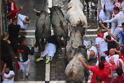 Un corredor cae entre dos toros en el sexto encierro de los Sanfermines.
