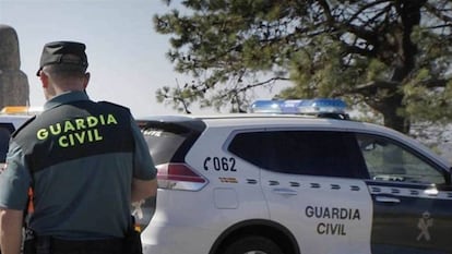 Un guardia civil delante de un coche patrulla, en una imagen de archivo.