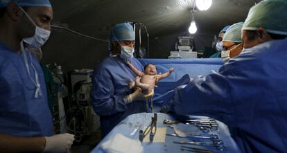 Un doctor marroquí sostiene a un niño sirio después de una cesárea en el campo de refugiados Al Zaatar en Mafrag (Jordania).