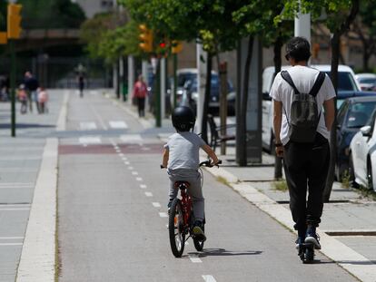 Un niño monta en bicicleta junto a su padre, que va en patinete.