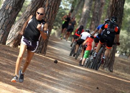 Un grupo de ciclistas se cruza con un corredor en la Casa de Campo.