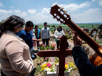 People visit the grave of a relative while a guitarist performs at the San Miguel Xico cementery on August 5, 2020, amid the COVID-19 coronavirus pandemic. (Photo by PEDRO PARDO / AFP)