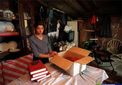 Una adolescente gitana en una chabola abre una caja llena de libros.