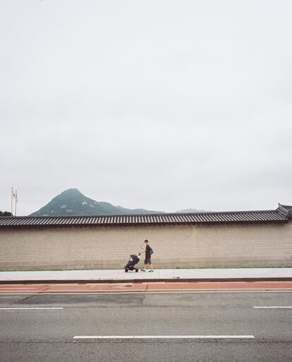 Un hombre empuja un carrito de niño a lo largo de la tapia del palacio Gyeongbokgung, el más grande de Seúl.