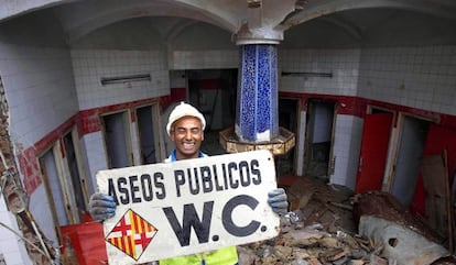 Un trabajador sostiene el cartel de los antiguos ba&ntilde;os p&uacute;blicos de la plaza Urquinaona.