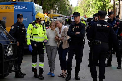 A first reponder assists two residents, as emergency services are searching for two people missing after a strong explosion injured 17 people in the Salamanca neighbourhood in Madrid, on May 6, 2022. - According to the latest report released by the emergency services, 17 injured have been taken care of. Four of them have been transferred to hospitals, including one in serious condition. (Photo by Pierre-Philippe MARCOU / AFP)
