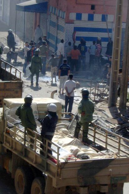Militares observan a ciudadanos marroquíes asaltar un comercio saharaui entre las calles de Skeikima y de Cherif Arradi de El Aaiún en la tarde del lunes.