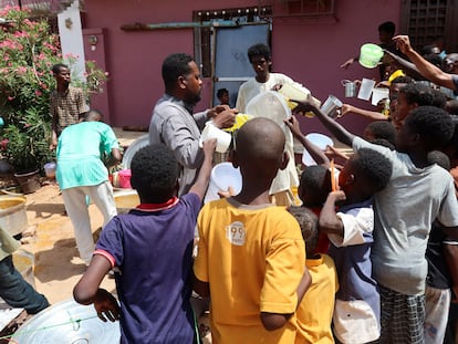 Varios niños sostienen recipientes vacíos mientras voluntarios distribuyen alimentos en la localidad sudanesa de Omdurman, el 3 de septiembre de 2023.