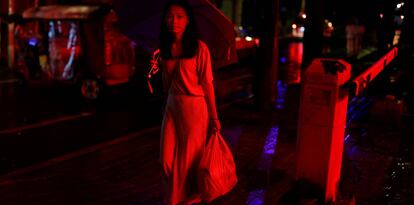 Uma mulher caminha em uma rua iluminada com neón no antigo distrito da cidade de Liwan em Guanghzou,