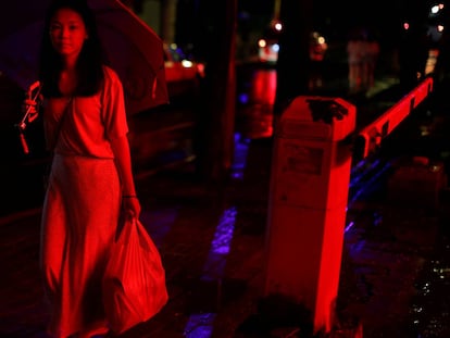 Uma mulher caminha em uma rua iluminada com neón no antigo distrito da cidade de Liwan em Guanghzou,