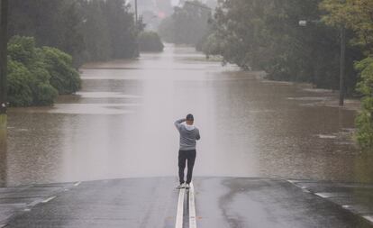 Un hombre hace una foto frente a una carretera inundada en el suburbio de McGraths Hill en Sydney, Australia. Hay advertencias de evacuación en partes del oeste de Sídney mientras las aguas siguen subiendo.