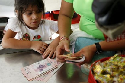 Uma criança olha enquanto sua mãe conta bolívares.