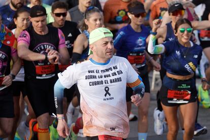 Un corredor con un mensaje en su camiseta que reza "Que el tiempo no borre lo que un da cubri el barro" durante la Maratn de Valencia.